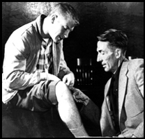 Yankees scout Tom Greenwade, who discovered Mickey for the Yankees, examines Mickey's knee. Mickey suffered a number of serious injuries throughout his career.